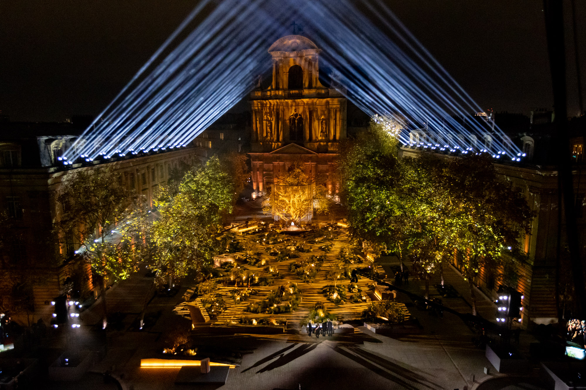 Des faisceaux croisés dessinent un temple de lumière au-dessus de la cérémonie