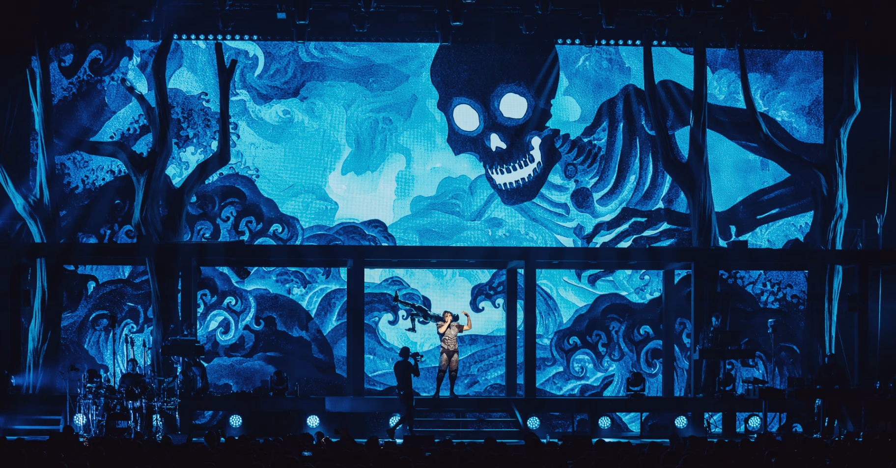 Orelsan devant une projection de squelette bleu