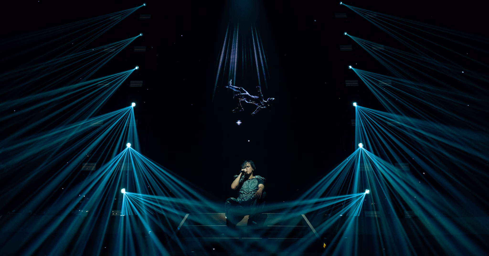 Orelsan au centre de faisceaux de lumière turquoise
