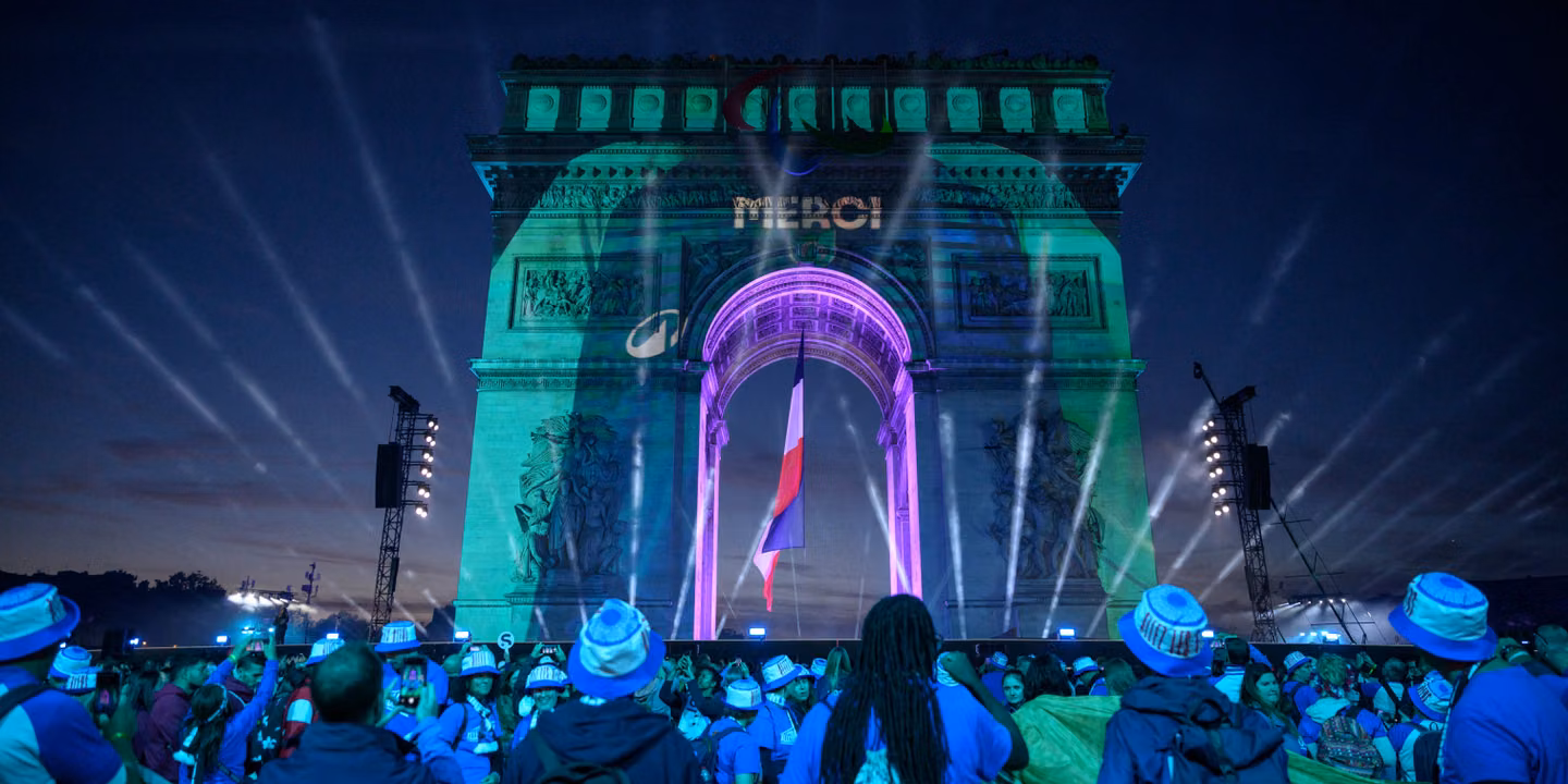 Arc de Triomphe éclairé en bleu et vert devant le public