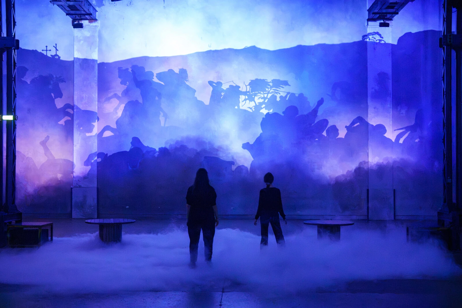 Silhouettes de cavaliers dans une projection bleue au-dessus de la brume