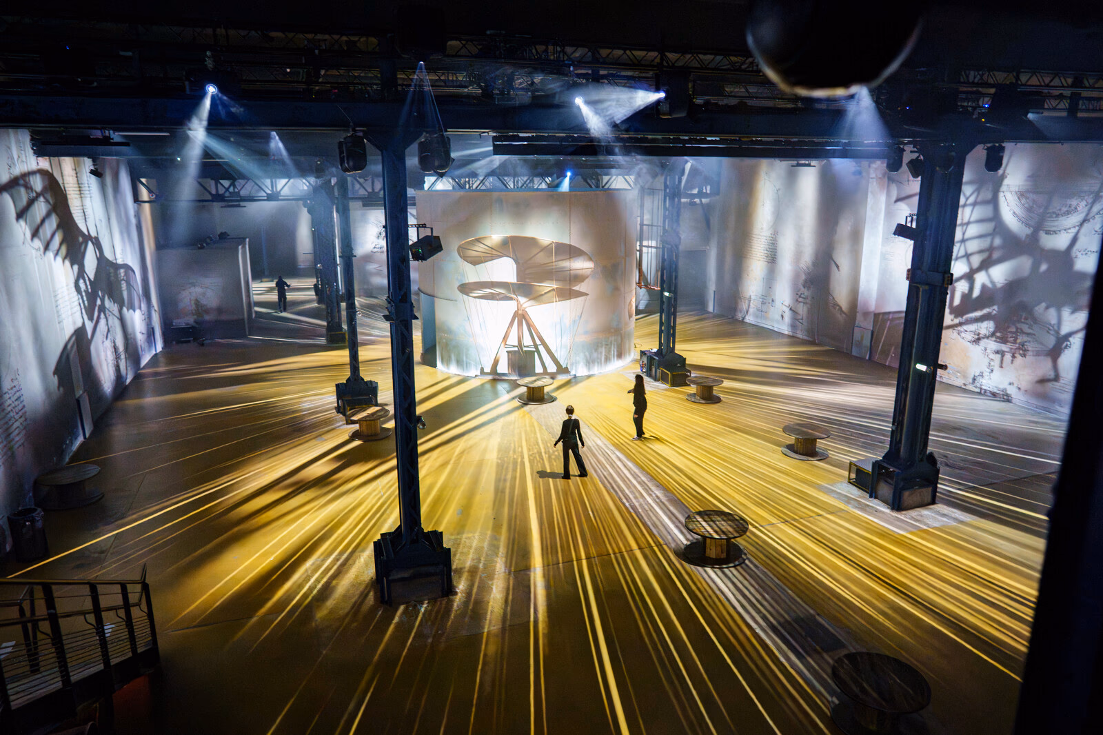 Vue en hauteur de la salle avec des projections et des faisceaux dorés